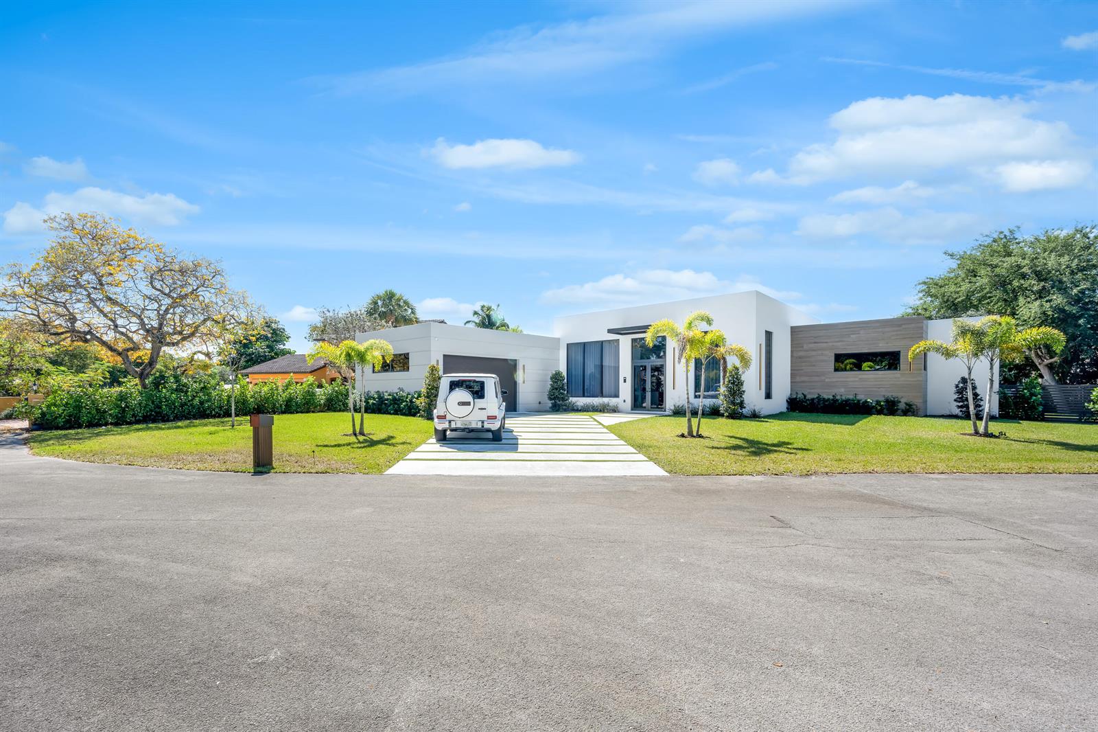 A modern, white single-story house with a paved driveway and a white SUV parked outside — 1000 SW 93rd Avenue, Plantation FL 33324, PLANTATION, FL