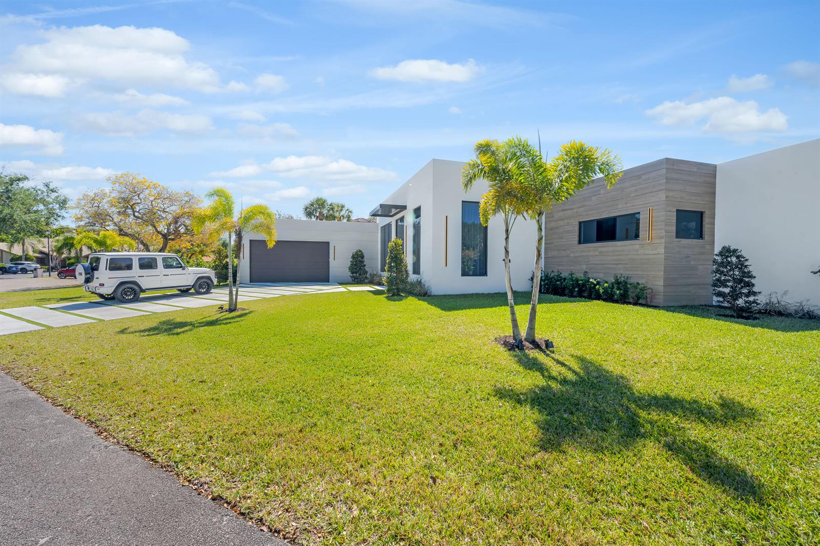 A modern, single-story house with a white facade, wood-paneled accent wall, and a white SUV — 1000 SW 93rd Avenue, Plantation FL 33324, PLANTATION, FL