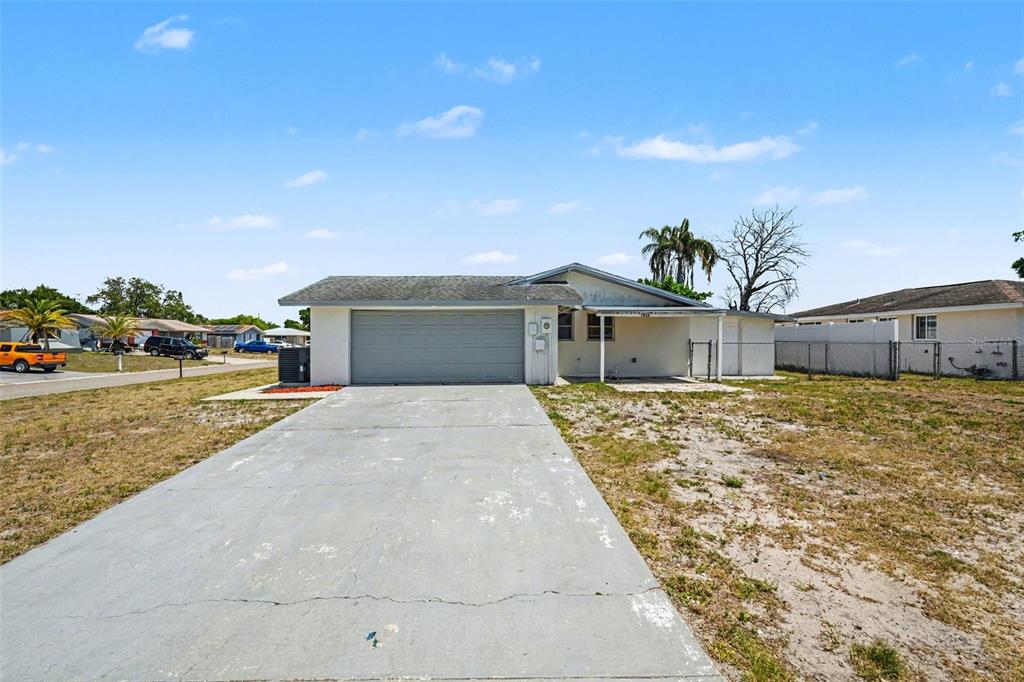 A single-story house with a gray garage door, concrete driveway, and a covered front porch — 7836 LOTUS DRIVE, PORT RICHEY, FL