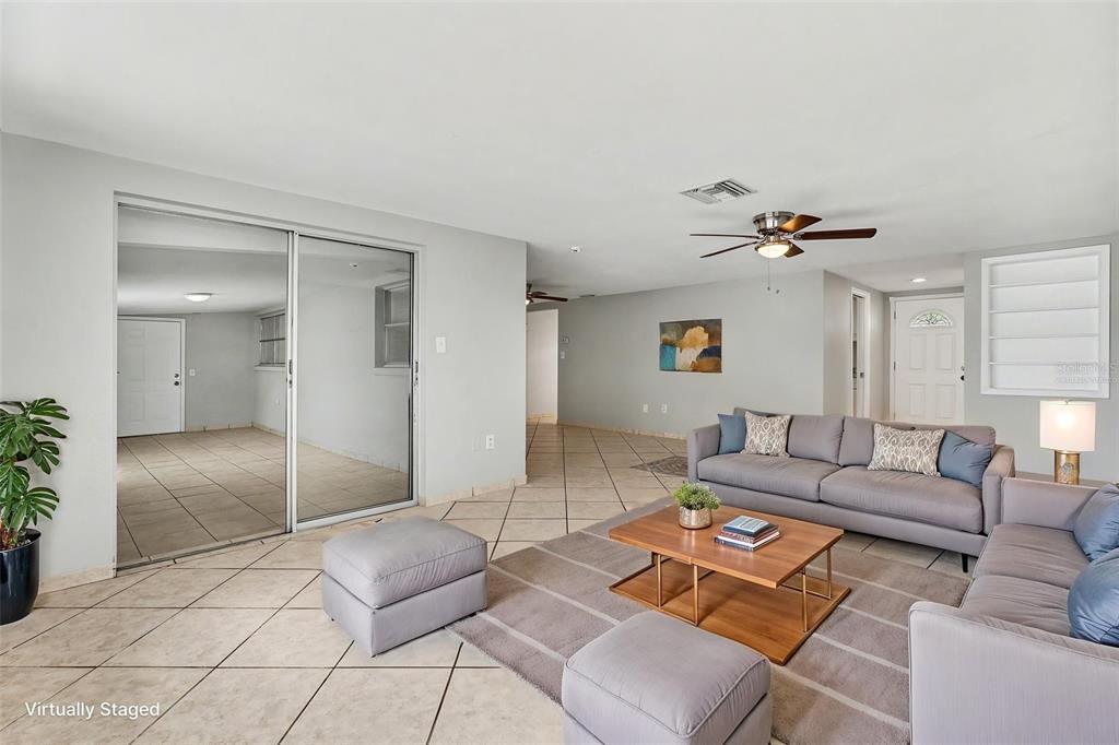 A living room with tile floors, a gray sofa, and a sliding glass door — 7836 LOTUS DRIVE, PORT RICHEY, FL