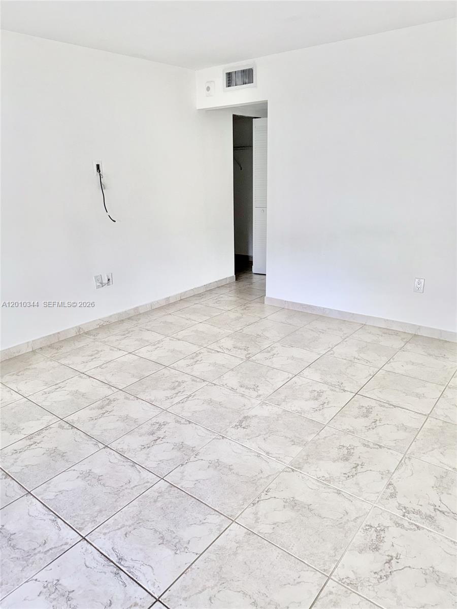 An empty room features white walls, light-colored tile flooring, and a doorway leading to a closet — 8933 SW 123rd Ct # 108, Miami FL 33186, MIAMI, FL