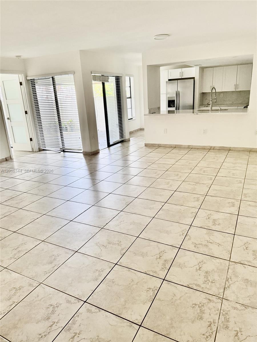An open-concept living area features light-colored tile flooring and a kitchen with white cabinets — 8933 SW 123rd Ct # 108, Miami FL 33186, MIAMI, FL