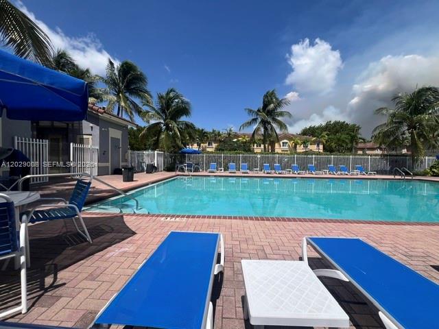 A swimming pool with lounge chairs on a brick patio under a blue sky — 8258 NW 108th Pl # 4, Doral FL 33178, DORAL, FL