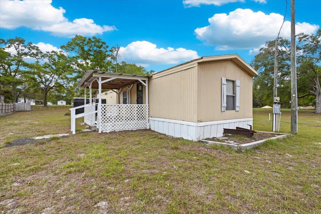 A tan mobile home with a small covered porch and white lattice skirting sits outdoors — 3100 NW 20TH STREET, BELL, FL