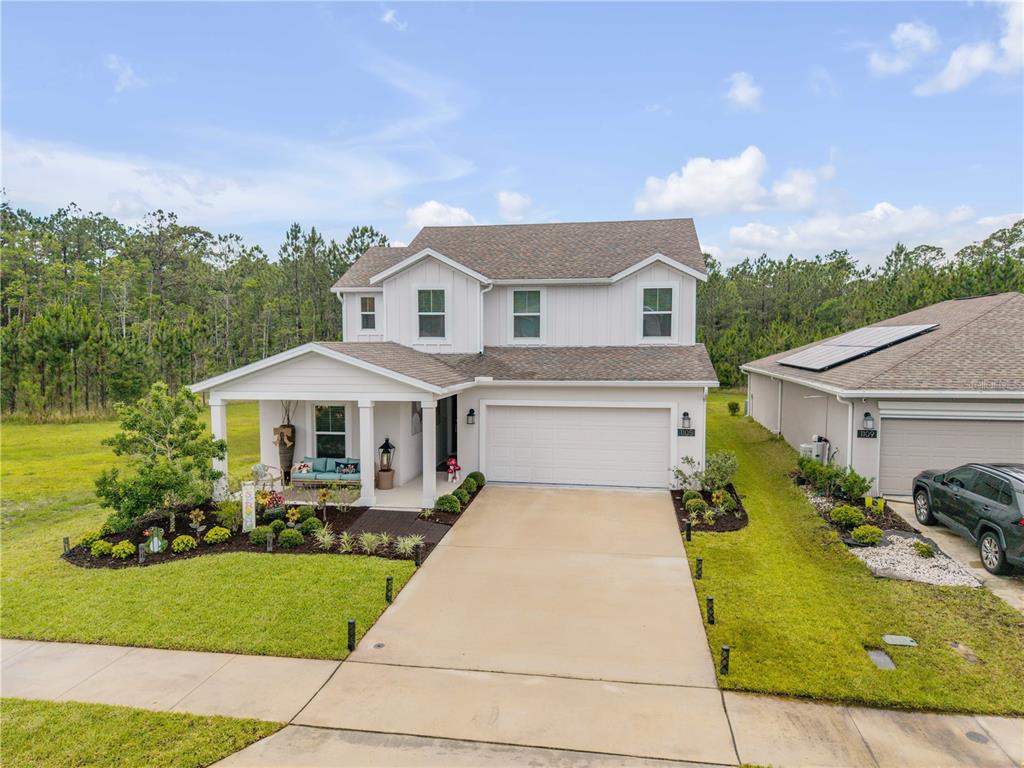 A two-story white house with a front porch, garage, and landscaped yard — 1105 PACIFIC DUNES COURT, DAYTONA BEACH, FL