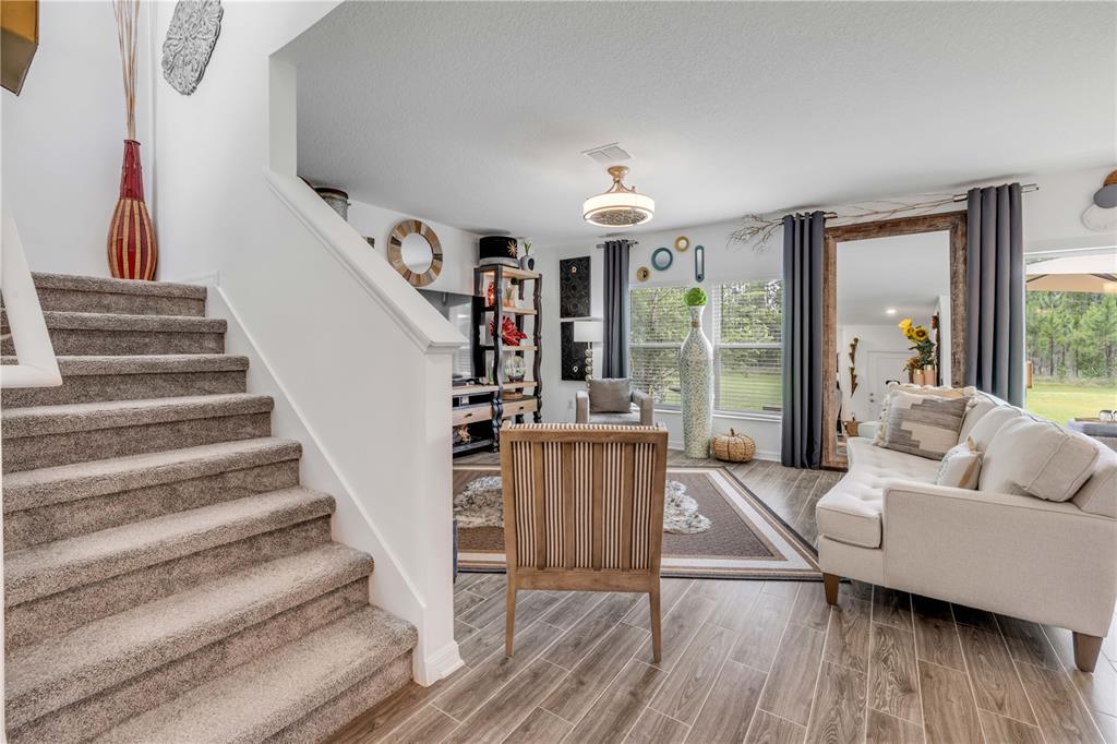 A carpeted staircase leads down to a living room with wood-look tile flooring — 1105 PACIFIC DUNES COURT, DAYTONA BEACH, FL