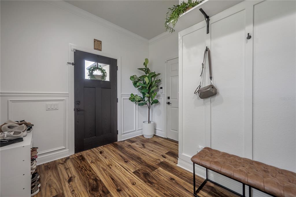 An entryway features wood-look flooring, a dark front door, a white bench, and wall molding — 4342 O ROURKE COURT, WESLEY CHAPEL, FL