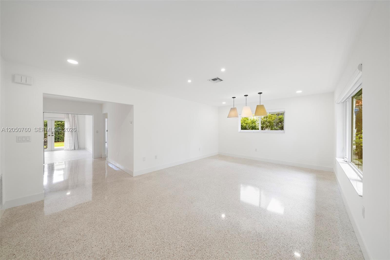 A bright, empty room features white walls, polished terrazzo flooring, and three hanging pendant lights — 415 Navarre Ave, Coral Gables FL 33134, CORAL GABLES, FL
