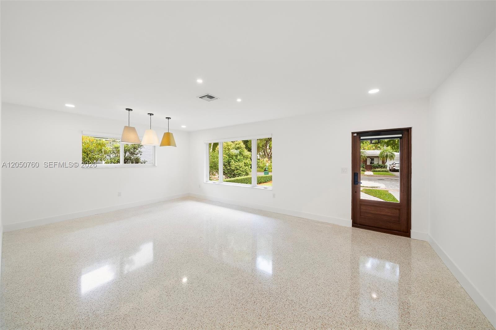 A bright, empty room features white walls, polished terrazzo floors, three pendant lights, and windows — 415 Navarre Ave, Coral Gables FL 33134, CORAL GABLES, FL