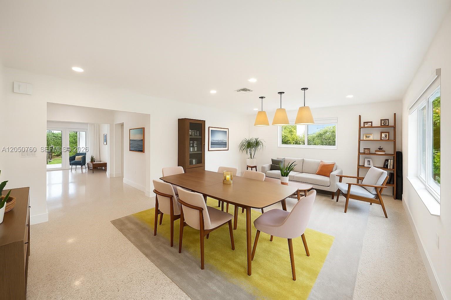 A dining and living area features a wooden table, light-colored chairs, and a yellow rug — 415 Navarre Ave, Coral Gables FL 33134, CORAL GABLES, FL