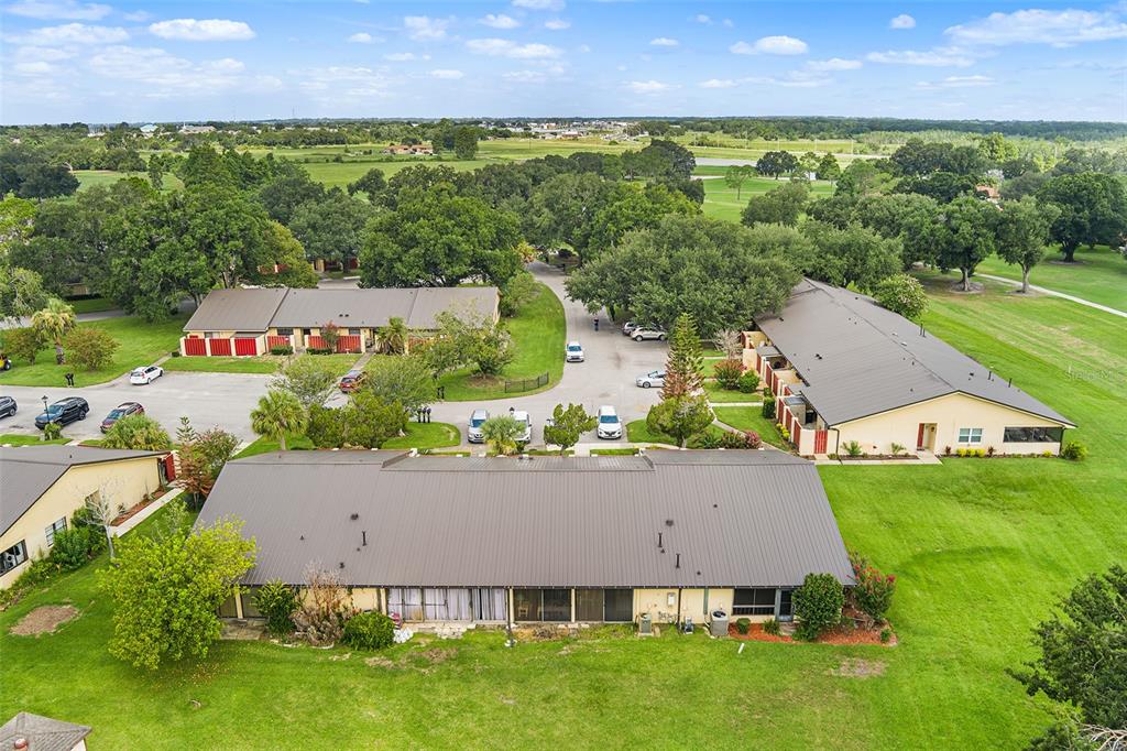 An aerial view shows three single-story residential buildings surrounded by green lawns and parking areas — 665 BROADMOOR CIRCLE, WINTER HAVEN, FL