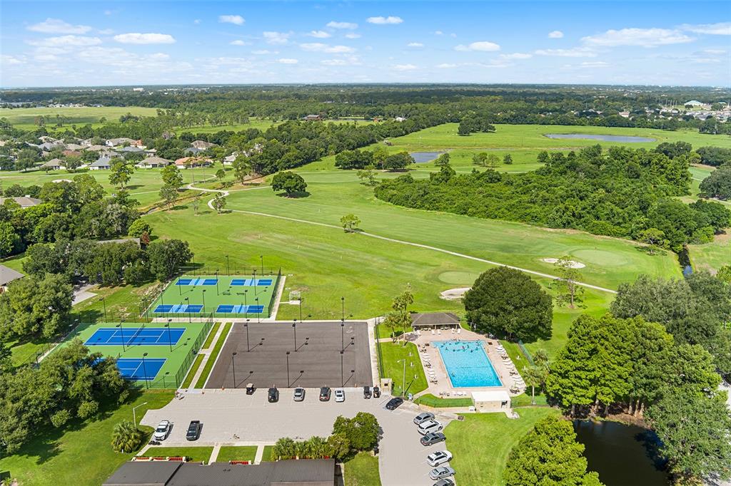 An aerial view shows tennis courts, a swimming pool, a parking lot, and a golf course — 665 BROADMOOR CIRCLE, WINTER HAVEN, FL