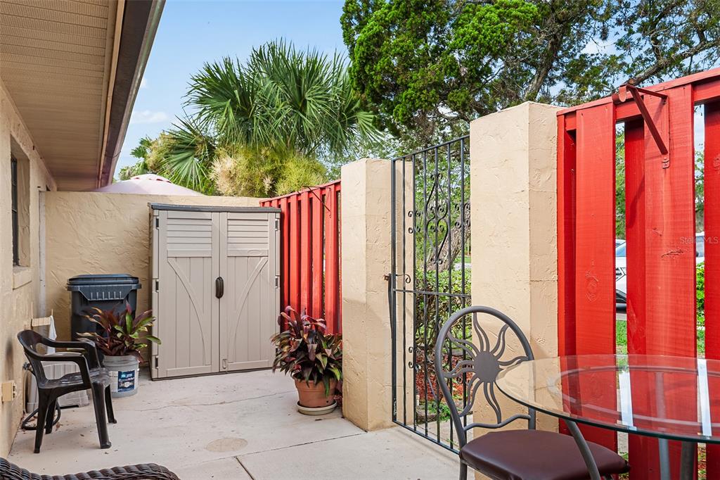 A concrete patio features a storage shed, a metal gate, and outdoor furniture — 665 BROADMOOR CIRCLE, WINTER HAVEN, FL