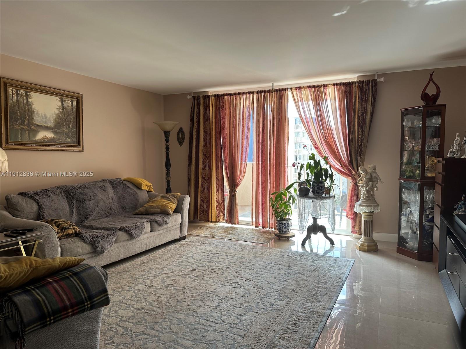 A living room features a grey sofa, a large area rug, and floor-to-ceiling curtains — 1865 S Ocean Dr # 6H, Hallandale Beach FL 33009, HALLANDALE BEACH, FL