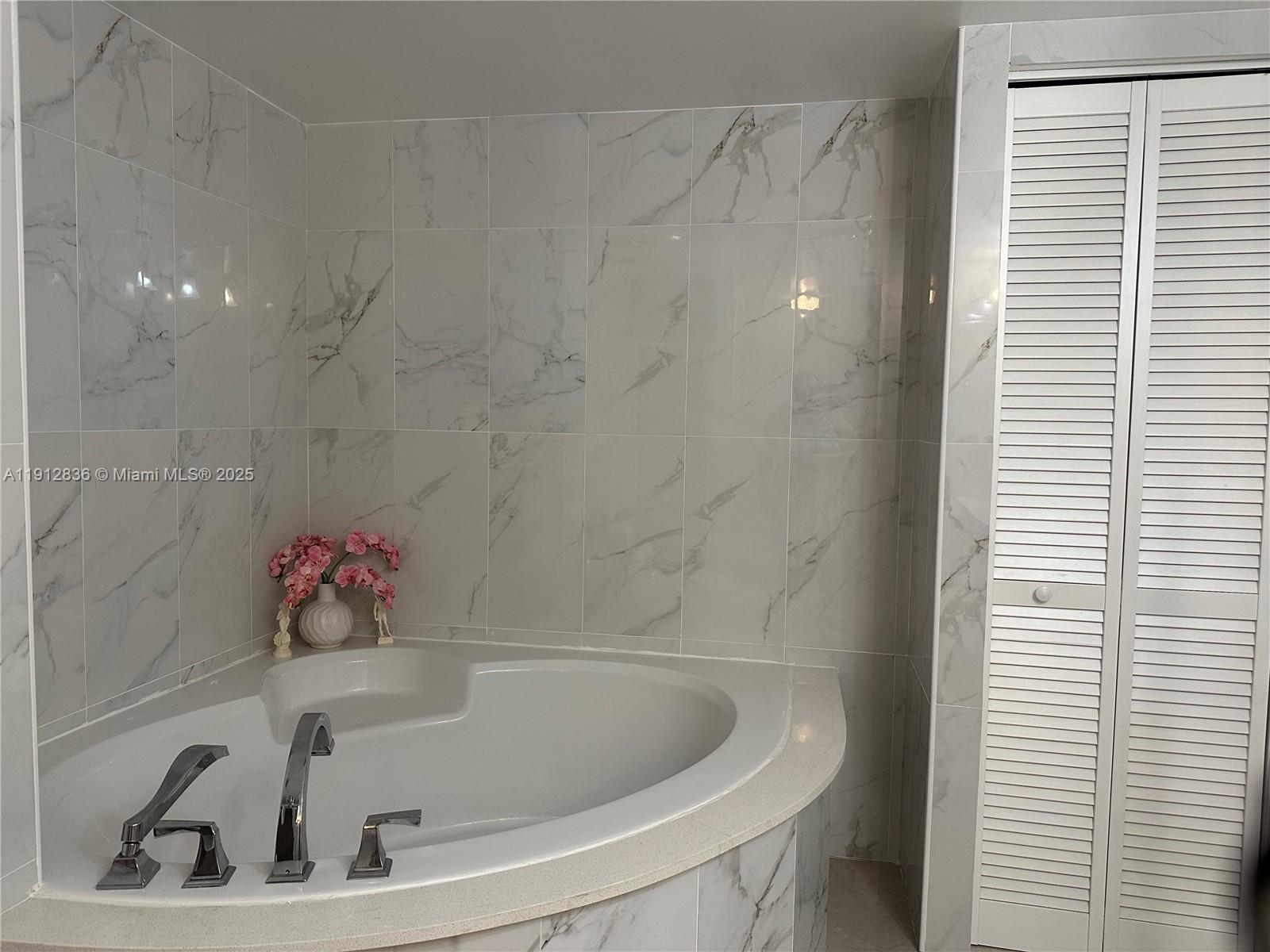 A corner bathtub with chrome fixtures is set against a white marble-tiled wall — 1865 S Ocean Dr # 6H, Hallandale Beach FL 33009, HALLANDALE BEACH, FL