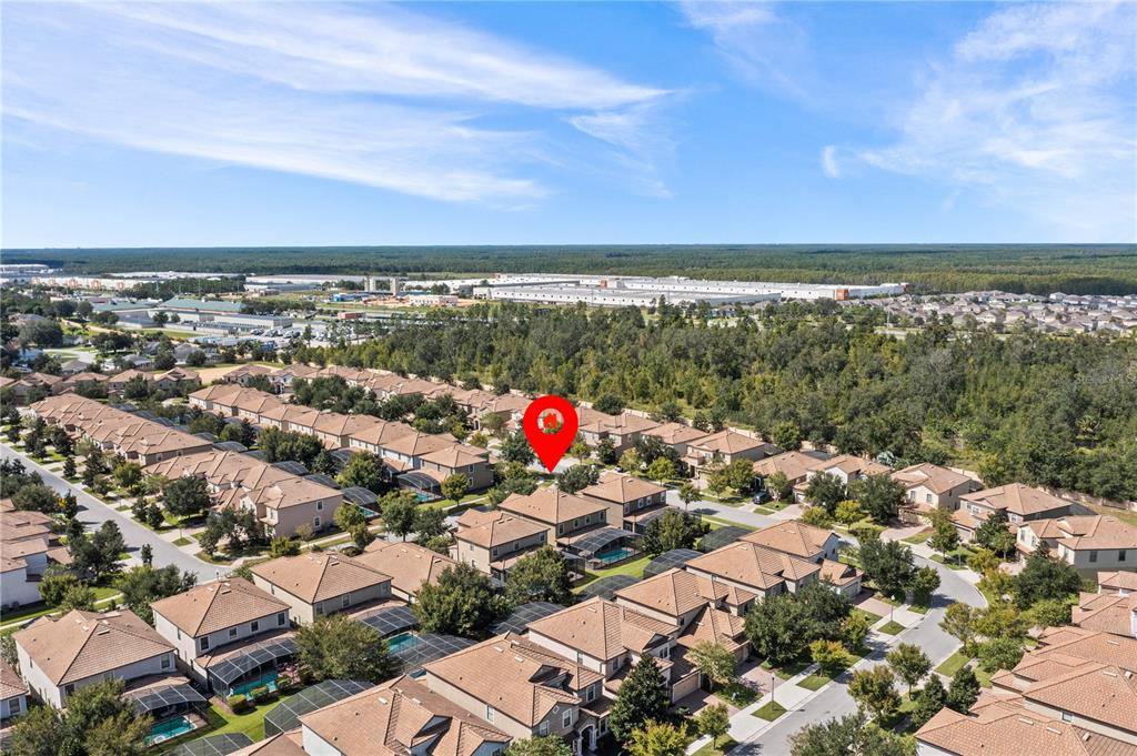 An aerial view shows a suburban neighborhood with many houses featuring brown roofs and pools — 9117 EL CARO LANE, DAVENPORT, FL