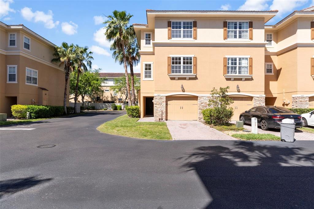 A three-story tan townhouse with a two-car garage and a paved driveway — 5621 BLACKFIN DRIVE, NEW PORT RICHEY, FL