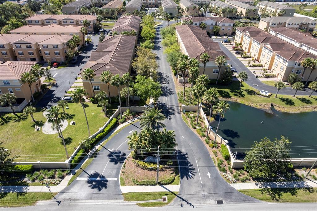 An aerial view shows the gated entrance to a residential apartment complex with a pond — 5621 BLACKFIN DRIVE, NEW PORT RICHEY, FL