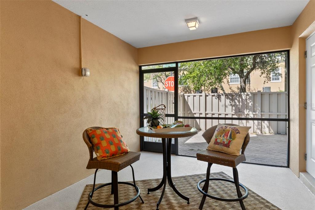 A screened-in patio features two wicker chairs, a small round table, and a paved courtyard — 5621 BLACKFIN DRIVE, NEW PORT RICHEY, FL