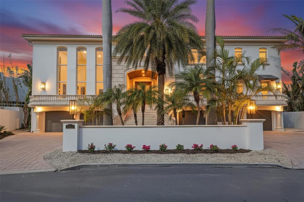 A large, multi-story white mansion with a palm-lined driveway and a sunset sky background — 4136 ROBERTS POINT CIRCLE, SARASOTA, FL