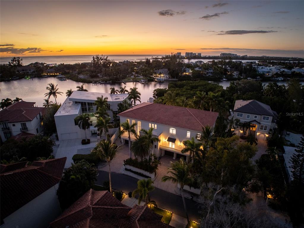 An aerial view shows a large multi-story house with a red tile roof at sunset — 4136 ROBERTS POINT CIRCLE, SARASOTA, FL