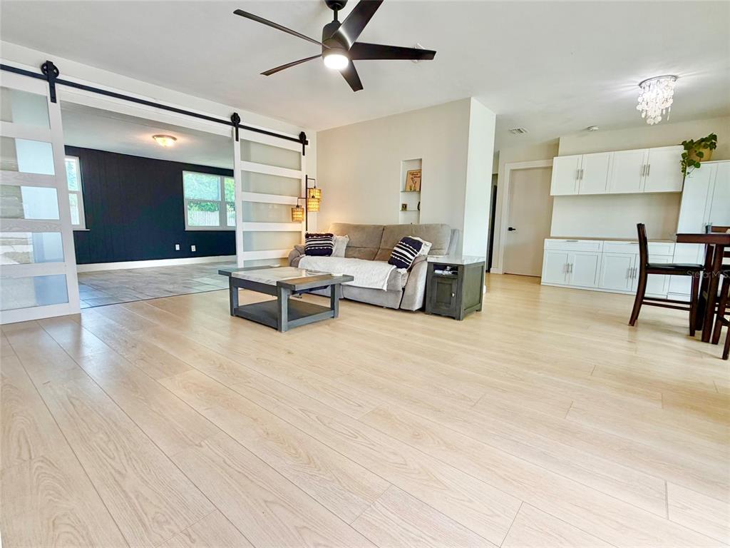 A living room features light wood flooring, a grey sofa, and sliding barn doors — 3300 58TH STREET N, ST PETERSBURG, FL