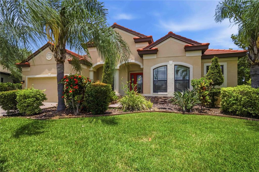 A single-story stucco house with a red tile roof, arched entryway, and landscaped front yard — 8057 RIO BELLA PLACE, UNIVERSITY PARK, FL