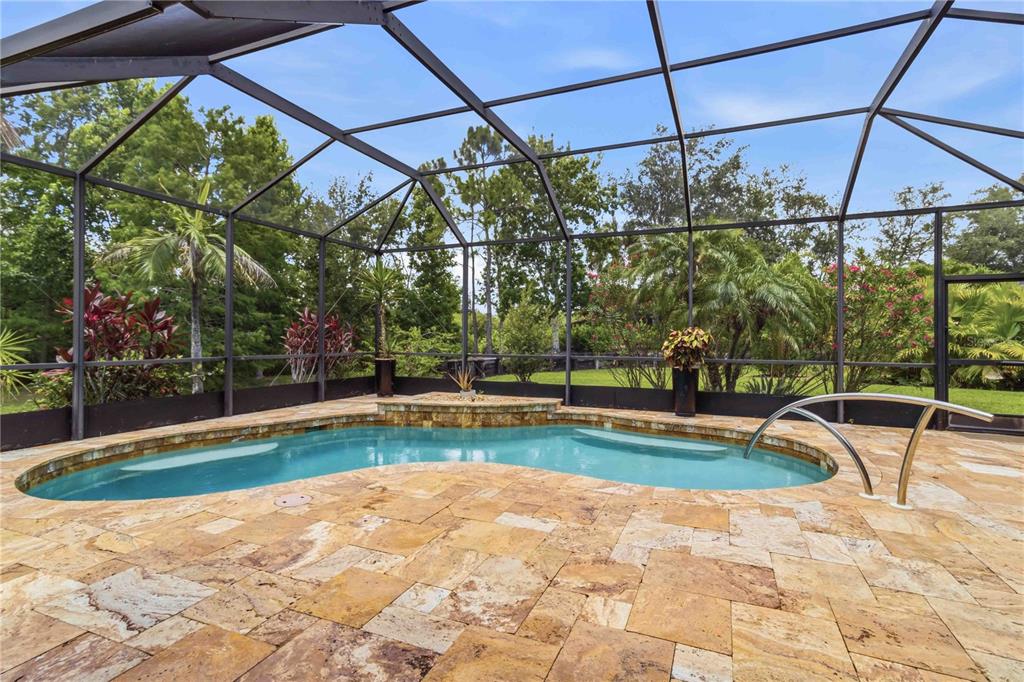 A screened-in pool area features a kidney-shaped pool with stone decking and lush landscaping — 8057 RIO BELLA PLACE, UNIVERSITY PARK, FL