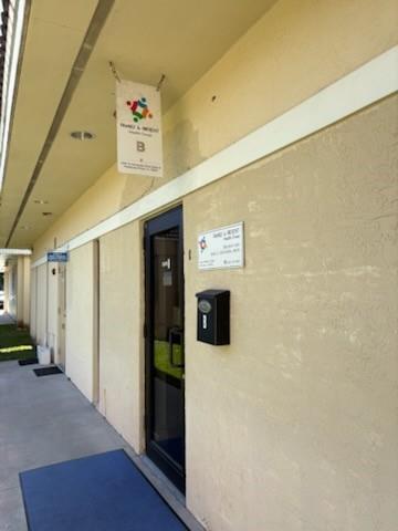 The exterior view shows a beige building entrance with a black door and hanging sign — PEMBROKE PINES, FL