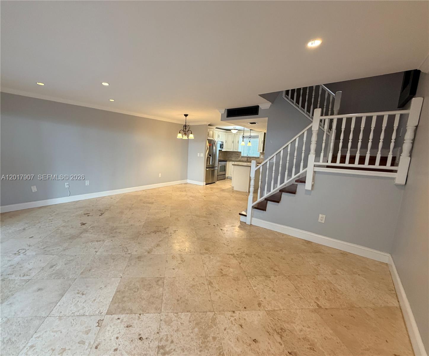 An open-concept living area features light-colored tile flooring, gray walls, and a wooden staircase — 3300 Atlanta # 15C, Hollywood FL 33021, HOLLYWOOD, FL