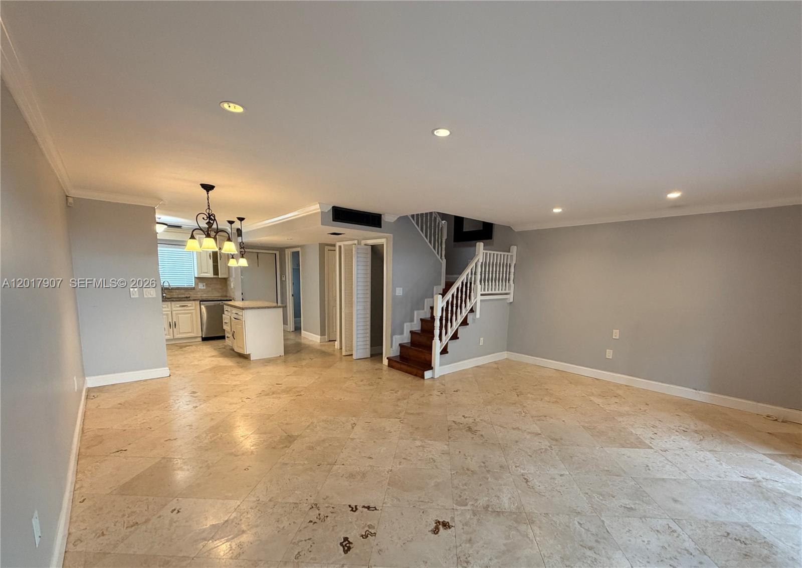An open-plan living area features light-colored tile flooring, a kitchen with white cabinetry, and a staircase — 3300 Atlanta # 15C, Hollywood FL 33021, HOLLYWOOD, FL