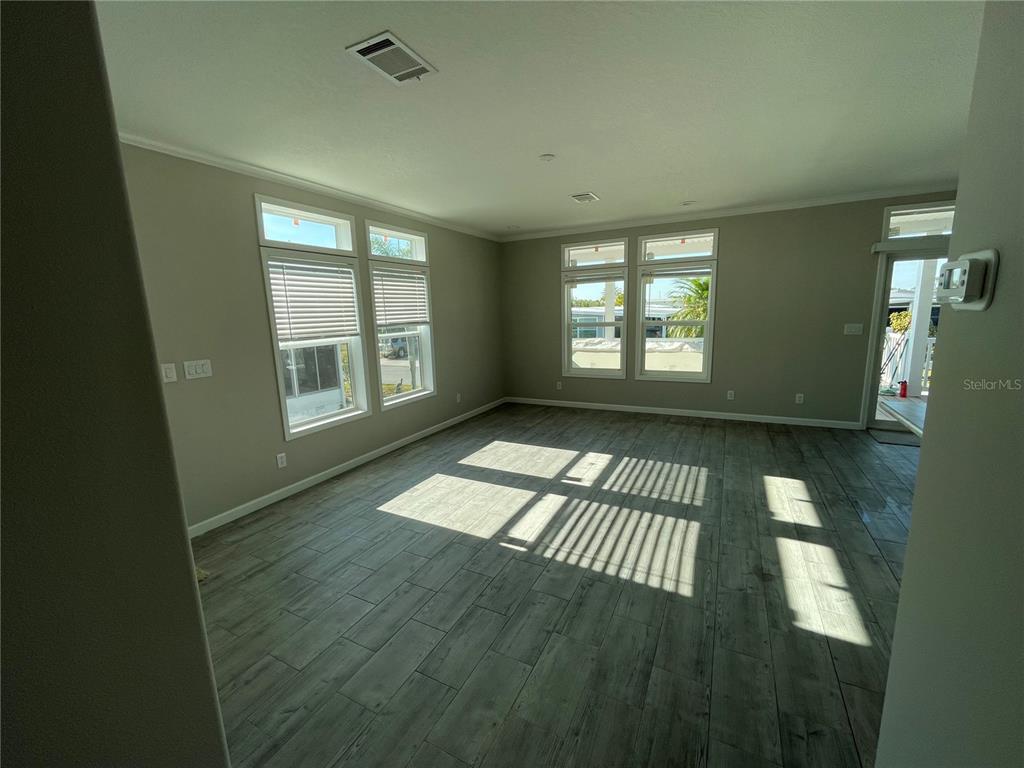 An empty living room features light gray walls, wood-look tile flooring, and multiple windows — 715 BLACKBURN BLVD, NORTH PORT, FL
