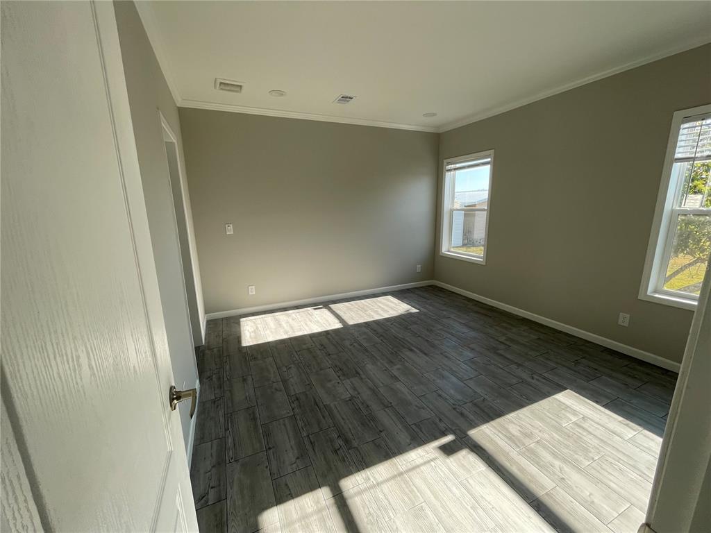 An empty room with gray wood-look tile flooring, light-colored walls, and two windows — 715 BLACKBURN BLVD, NORTH PORT, FL