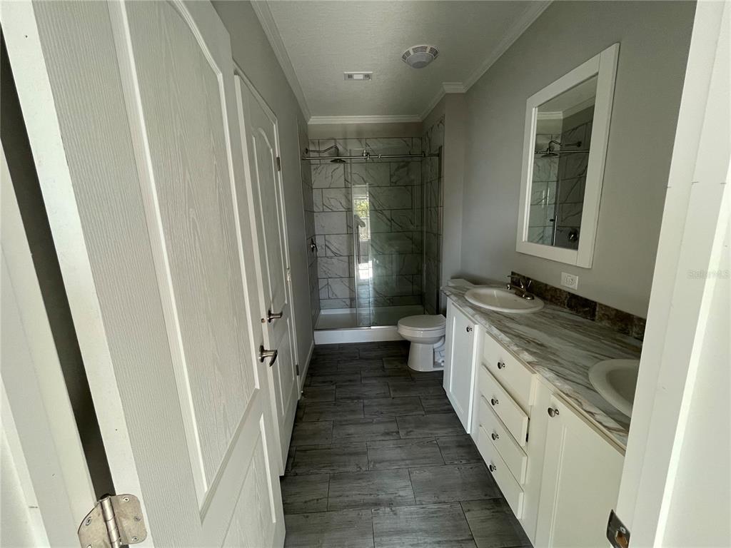 A bathroom features a glass-enclosed shower, a white vanity with a stone countertop, and tile flooring — 715 BLACKBURN BLVD, NORTH PORT, FL