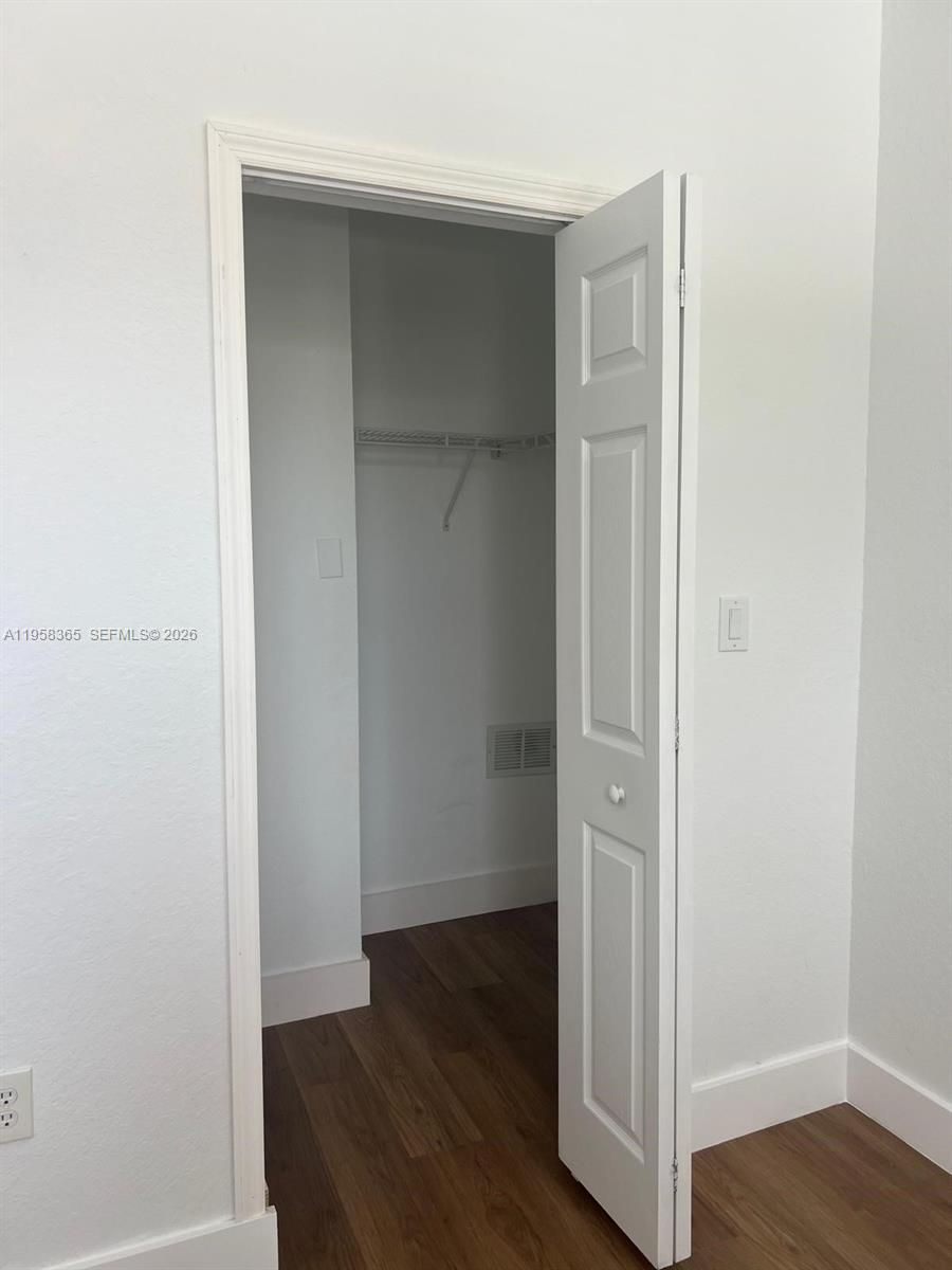 An open door reveals a small closet with a white wire shelf and wood flooring — 10738 NW 80th Ln, Doral FL 33178, DORAL, FL