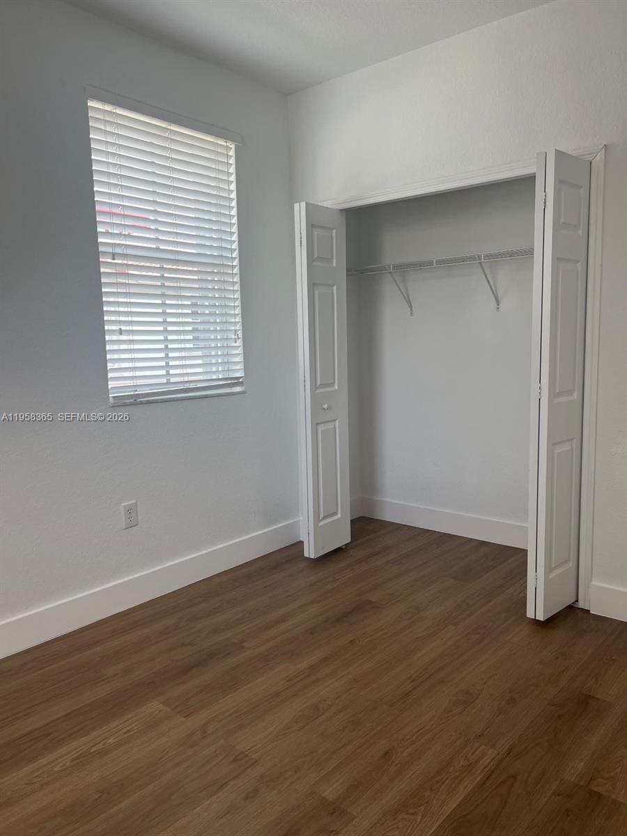 This bedroom features light-colored walls, wood-look flooring, a window with blinds, and a closet — 10738 NW 80th Ln, Doral FL 33178, DORAL, FL