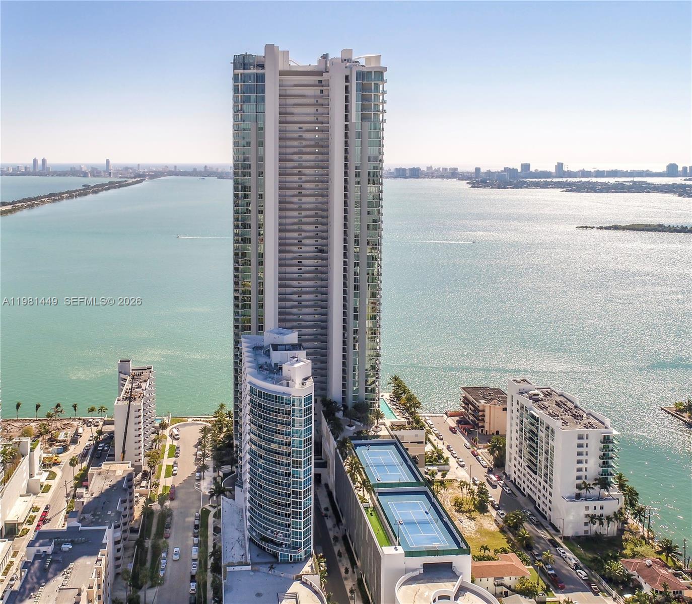 An aerial view shows a tall residential skyscraper surrounded by water and smaller buildings — 2900 NE 7th Ave # 404, Miami FL 33137, MIAMI, FL