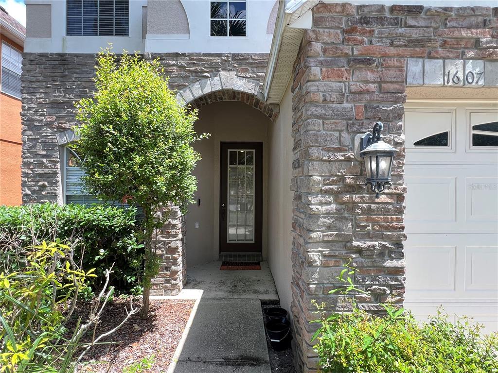 The exterior of a house features a stone facade, a front door, and a garage — 1607 TAIL FEATHER DRIVE, KISSIMMEE, FL