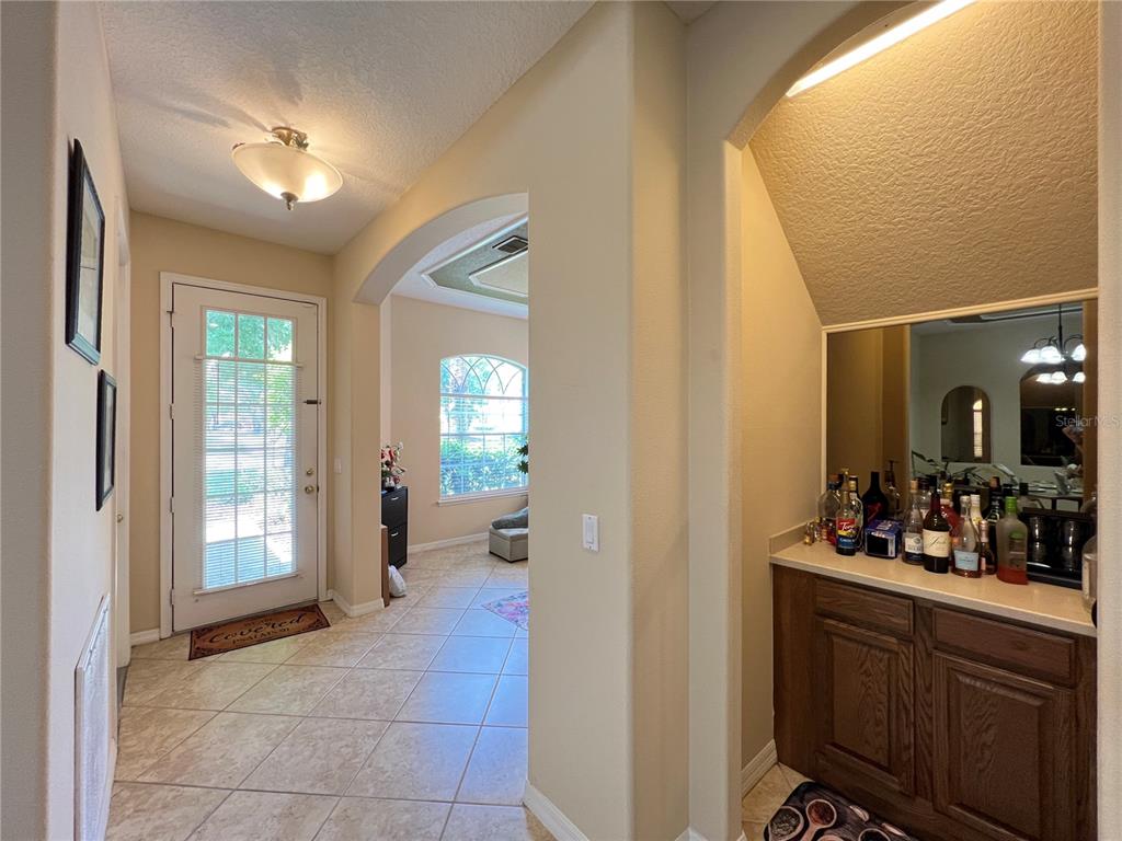 An entryway with tiled floors leads to a living area and a built-in wet bar — 1607 TAIL FEATHER DRIVE, KISSIMMEE, FL
