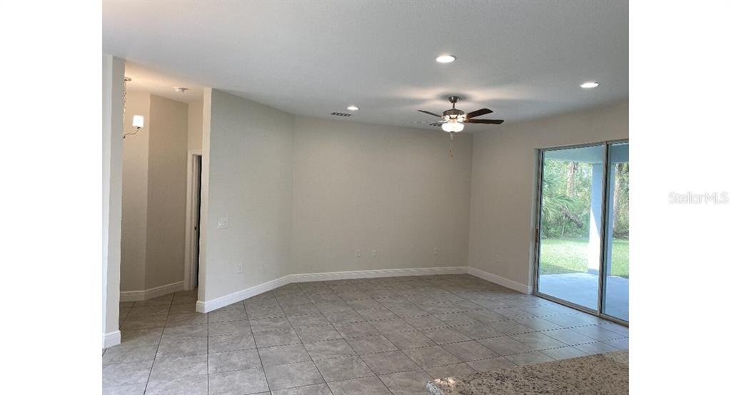 An open living area features tile flooring, a ceiling fan, and sliding glass doors — 7724 SWISS AVENUE, NORTH PORT, FL