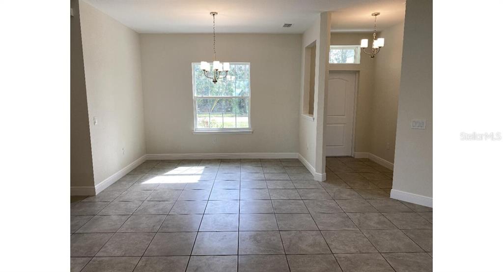 A dining area with tile flooring, a large window, and two hanging light fixtures — 7724 SWISS AVENUE, NORTH PORT, FL