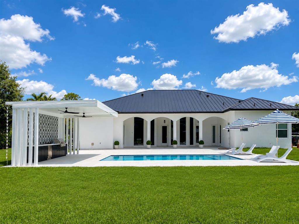 A white house with a metal roof, swimming pool, and covered outdoor kitchen area — 23710 SW 214TH PLACE, HOMESTEAD, FL