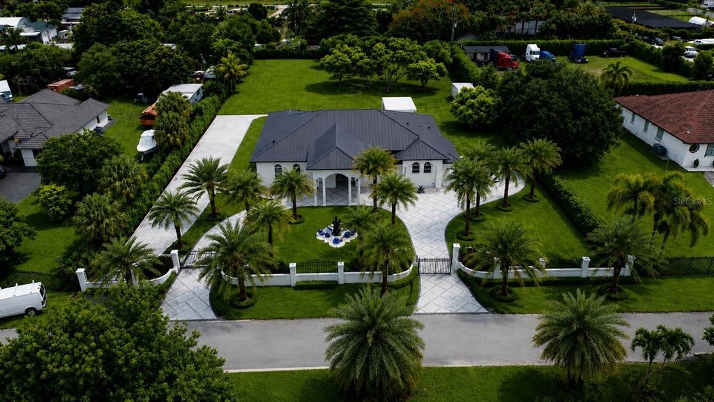 An aerial view shows a house with a dark roof, circular driveway, and palm trees — 23710 SW 214TH PLACE, HOMESTEAD, FL