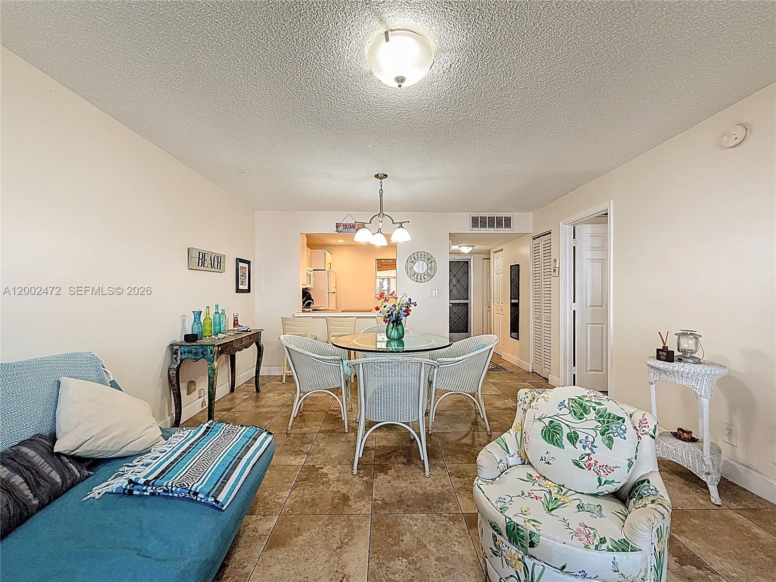 A living and dining area features tile floors, a glass table, and wicker chairs — 410 SE 2nd St # 115, Hallandale Beach FL 33009, HALLANDALE BEACH, FL