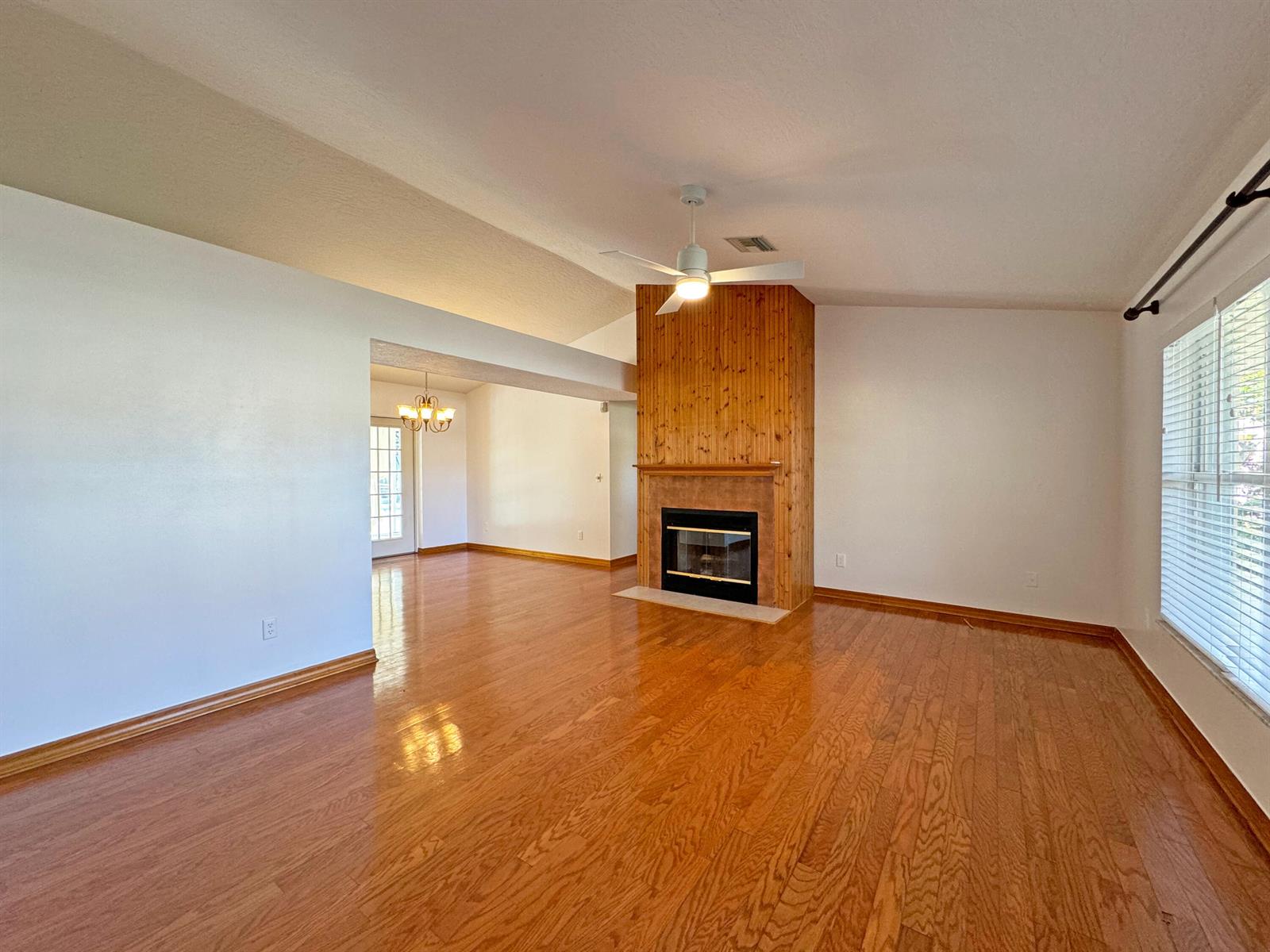 A living room with hardwood floors, a wood-paneled fireplace, and an adjacent dining area — 495 11th Court, Vero Beach FL 32962, VERO BEACH, FL