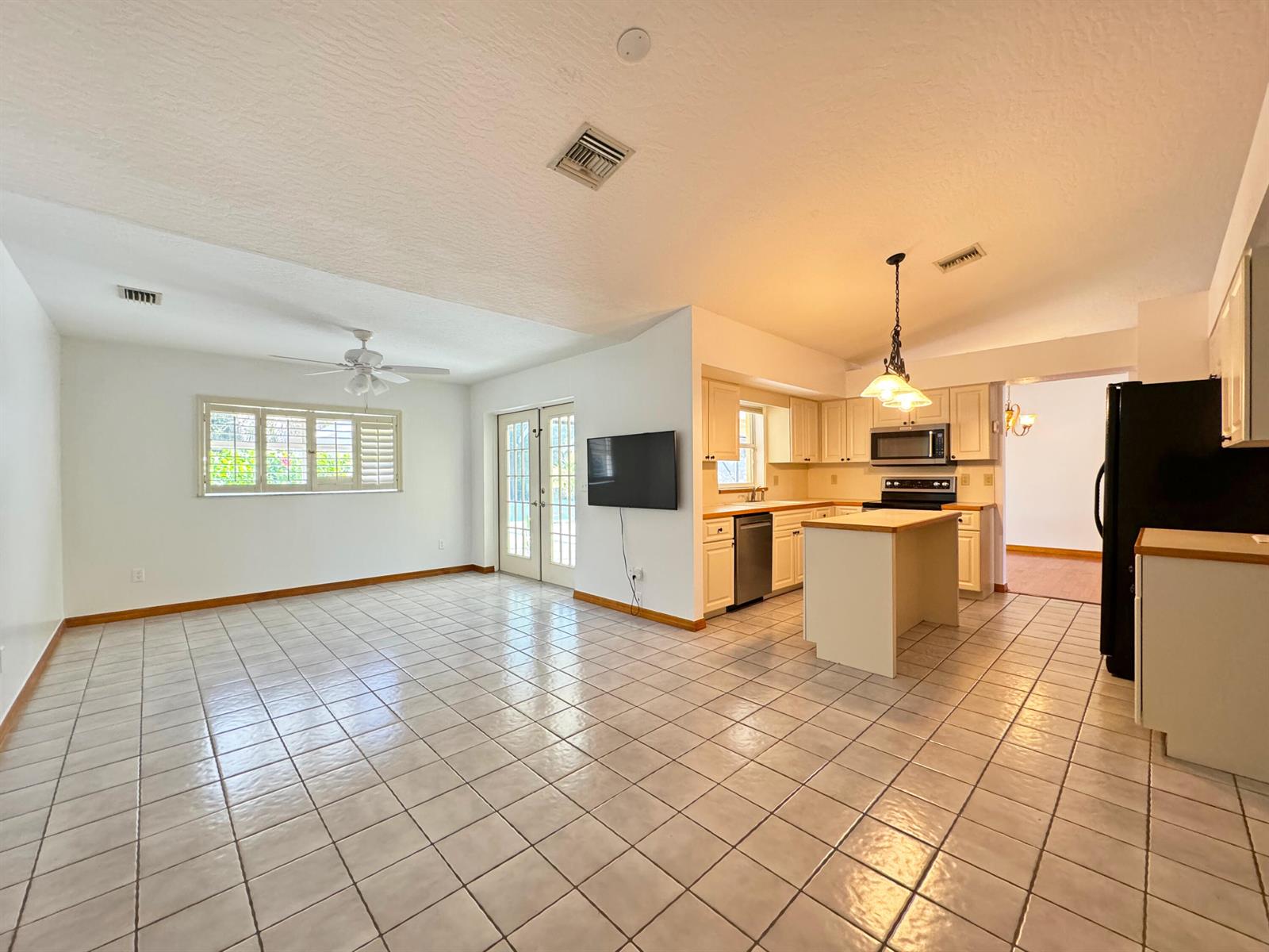 An open-concept living area features white tile flooring, a kitchen with an island, and cabinetry — 495 11th Court, Vero Beach FL 32962, VERO BEACH, FL