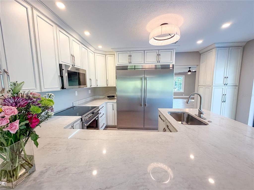 A kitchen features white cabinetry, stainless steel appliances, and a large marble-topped island — 410 SW 56TH AVENUE, PLANTATION, FL