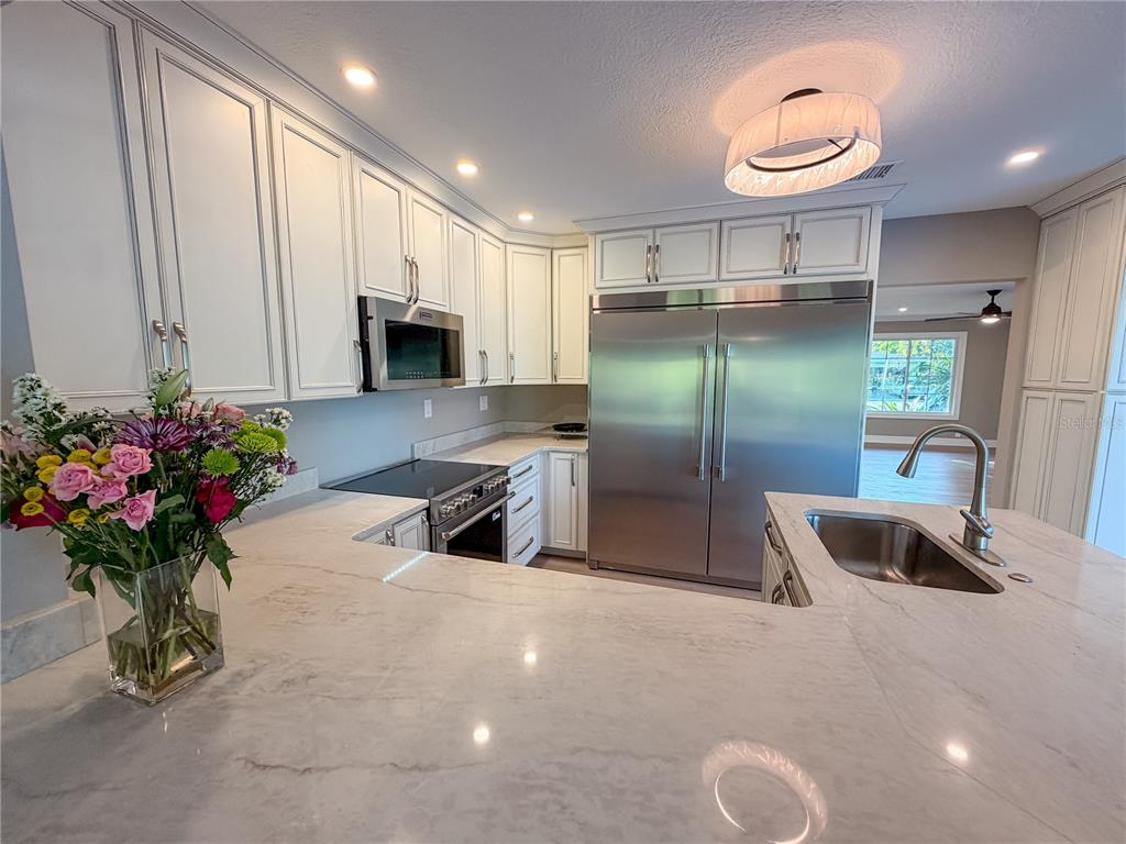 A kitchen features white cabinetry, stainless steel appliances, and a large marble-topped island with sink — 410 SW 56TH AVENUE, PLANTATION, FL