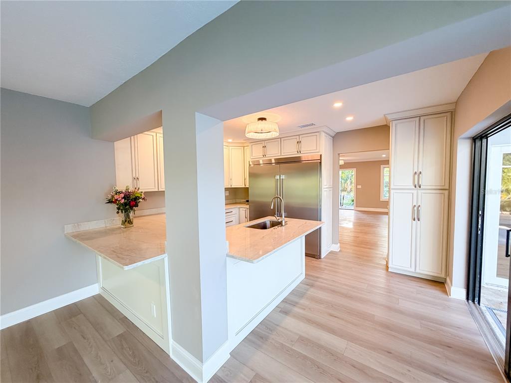 A kitchen features white cabinetry, stainless steel appliances, a center island, and light wood flooring — 410 SW 56TH AVENUE, PLANTATION, FL