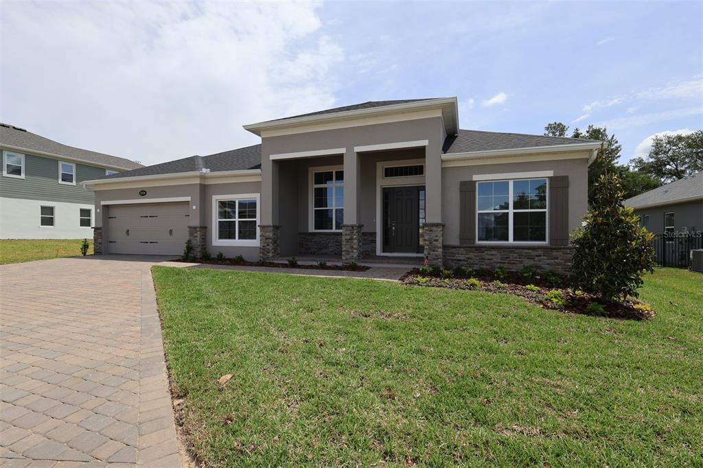 A single-story house with a gray stucco exterior, stone accents, and a paved driveway — 3270 WOLF LAKE AVENUE, APOPKA, FL